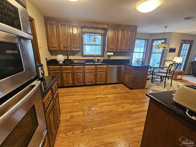 kitchen featuring dishwasher, visible vents, light wood finished floors, and a sink