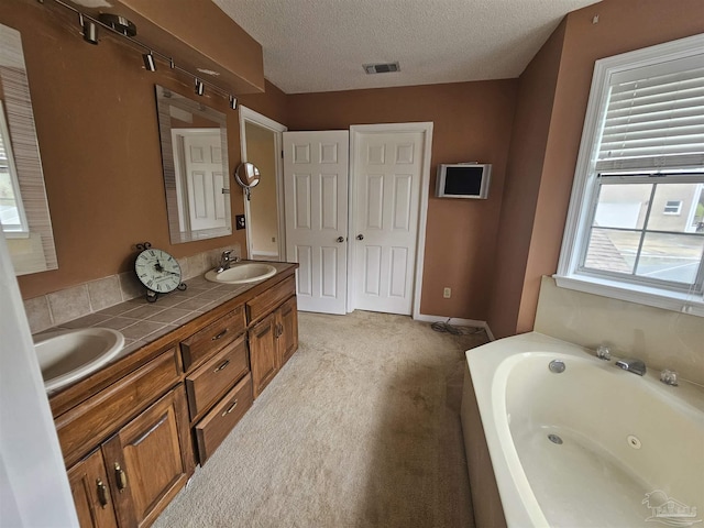 full bathroom with a sink, visible vents, a textured ceiling, and a tub with jets