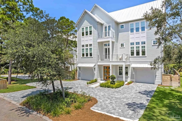 coastal home with a garage, metal roof, and decorative driveway