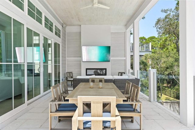 sunroom / solarium with a fireplace, wood ceiling, and a ceiling fan