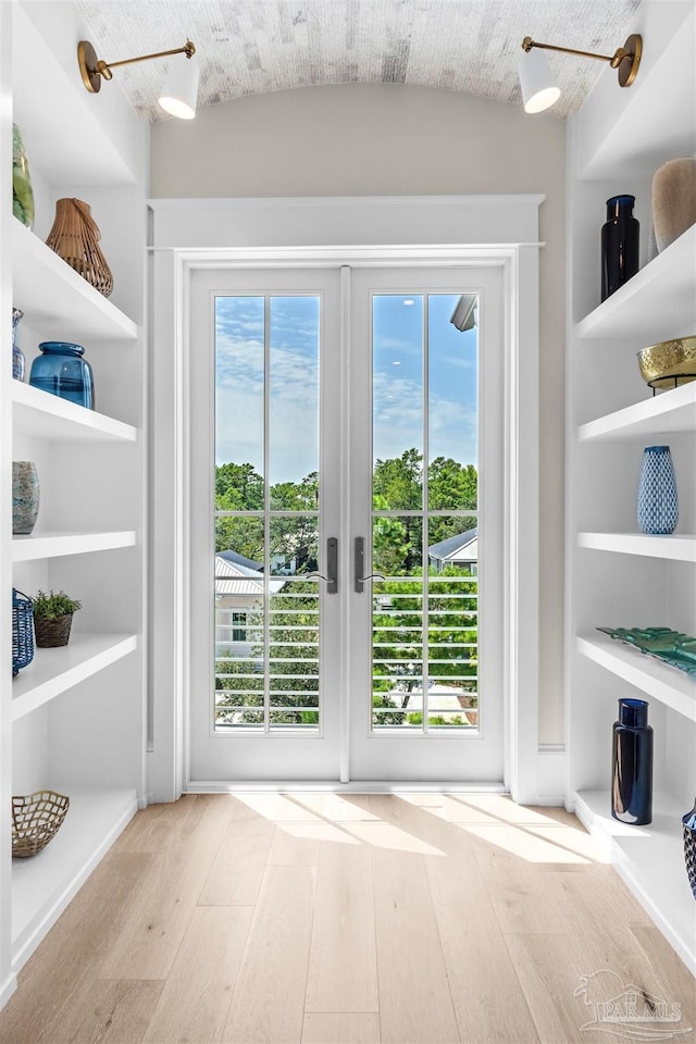 doorway to outside with wood-type flooring, built in shelves, and french doors