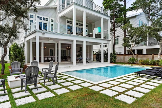 back of property featuring a patio, fence, a balcony, and an outdoor pool