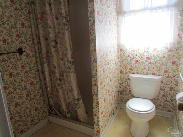 bathroom featuring baseboards, a stall shower, toilet, and wallpapered walls