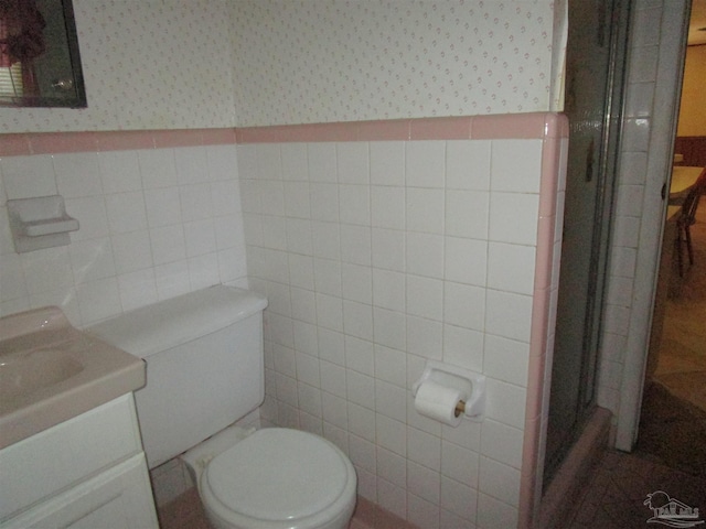 bathroom featuring toilet, a wainscoted wall, tile walls, a stall shower, and wallpapered walls