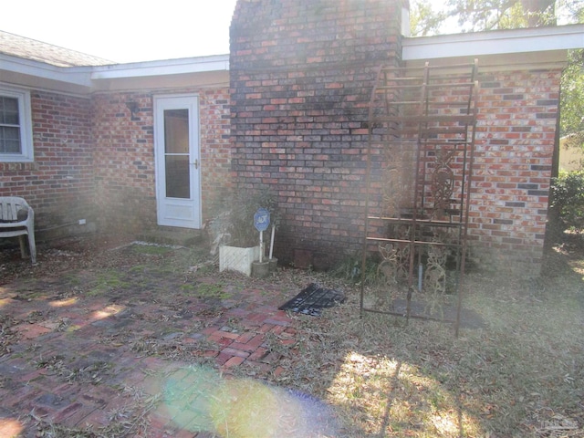 view of side of home featuring brick siding and a patio area