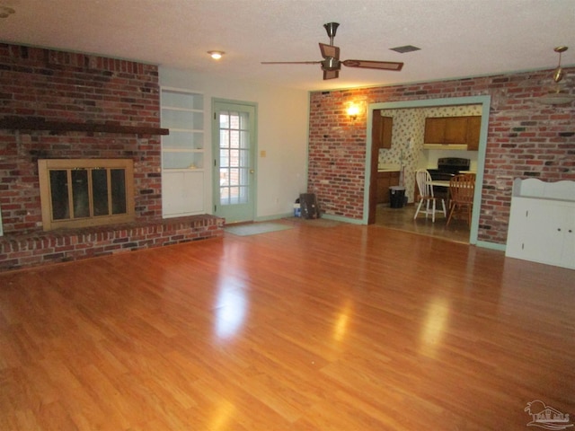 unfurnished living room featuring ceiling fan, a fireplace, a textured ceiling, and wood finished floors