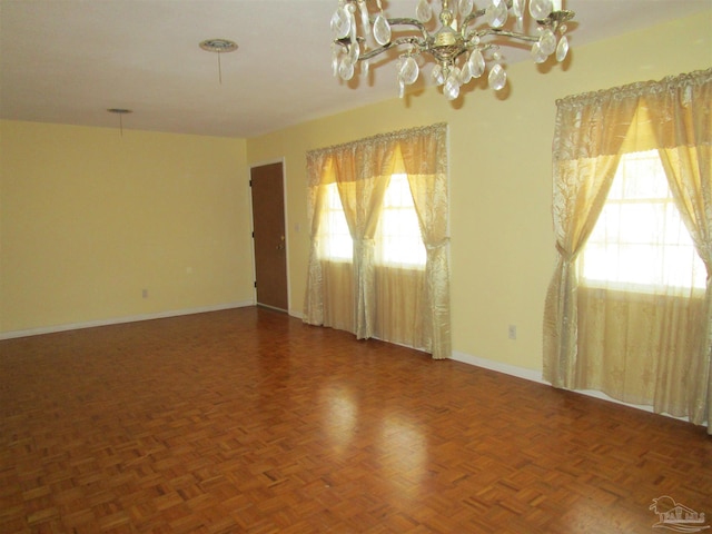 empty room with baseboards and an inviting chandelier