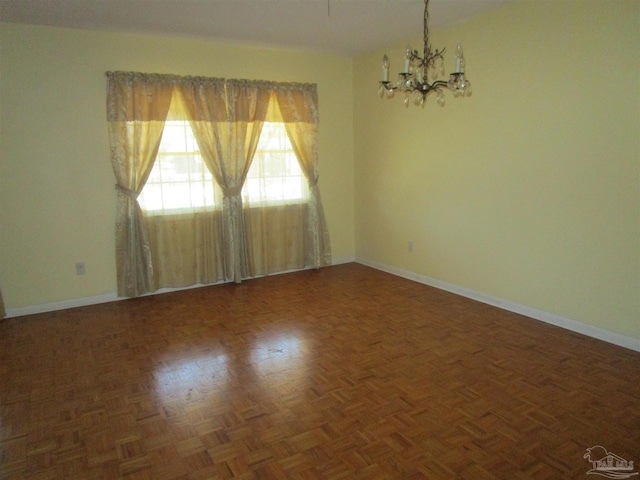 spare room with a chandelier and baseboards