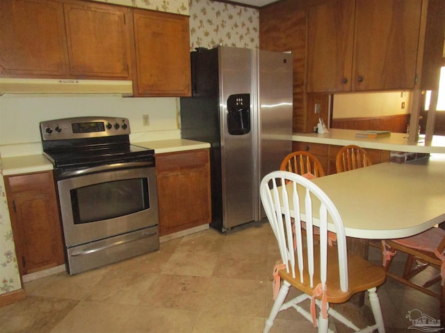 kitchen featuring stainless steel appliances, brown cabinetry, light countertops, and under cabinet range hood