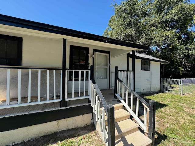 property entrance featuring a wooden deck and a yard