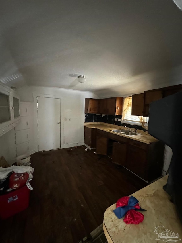 kitchen with dark wood-type flooring, vaulted ceiling, and sink