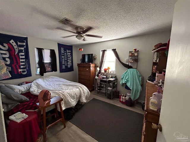 bedroom with ceiling fan, hardwood / wood-style flooring, and a textured ceiling