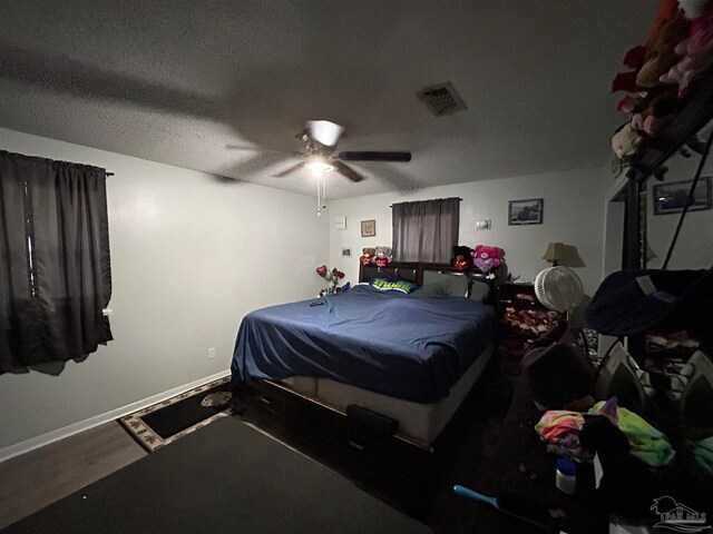 bedroom with hardwood / wood-style flooring, ceiling fan, and a textured ceiling