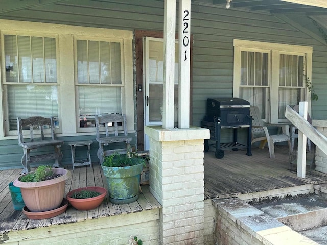 wooden terrace featuring a porch and area for grilling