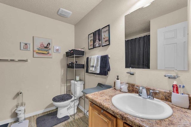 bathroom with vanity, wood-type flooring, a textured ceiling, and toilet