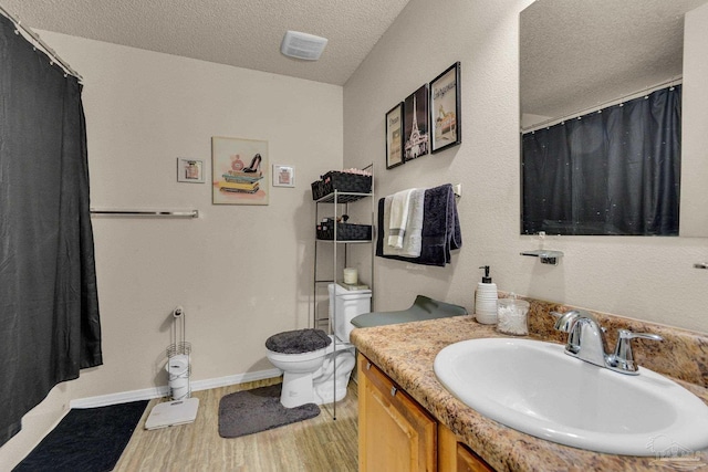 bathroom featuring hardwood / wood-style flooring, vanity, a textured ceiling, and toilet