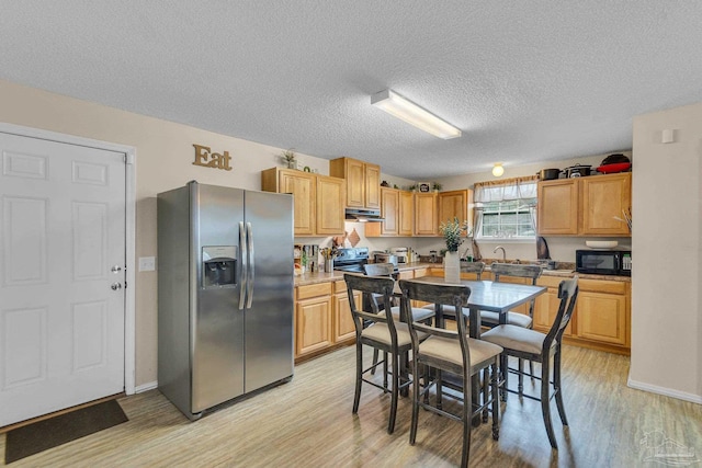 kitchen featuring stainless steel fridge, light hardwood / wood-style flooring, and a textured ceiling