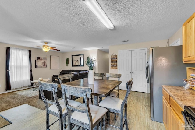 dining space featuring a textured ceiling, ceiling fan, and light hardwood / wood-style flooring