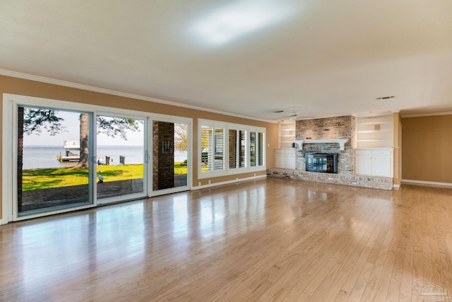 unfurnished living room with crown molding, baseboards, light wood finished floors, and a fireplace