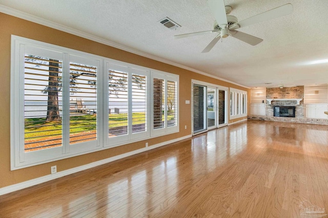 unfurnished living room with plenty of natural light, a ceiling fan, wood finished floors, visible vents, and ornamental molding