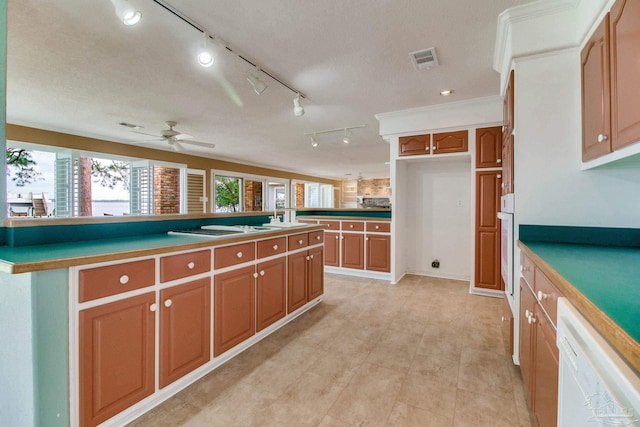 kitchen featuring visible vents, brown cabinetry, white appliances, a center island, and a ceiling fan