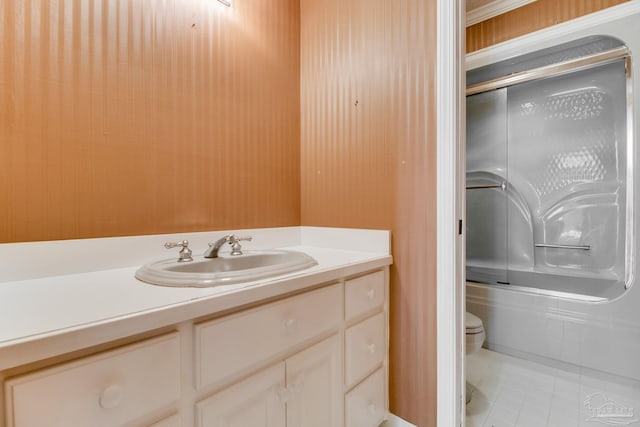 bathroom featuring vanity, tile patterned flooring, enclosed tub / shower combo, and toilet