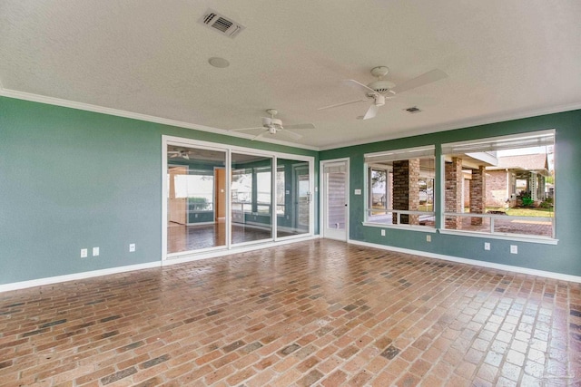 unfurnished room featuring visible vents, ornamental molding, ceiling fan, and brick floor