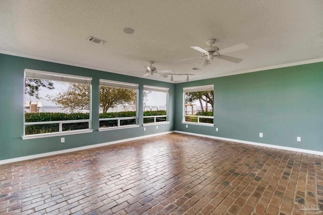 empty room featuring ceiling fan, brick floor, a textured ceiling, baseboards, and visible vents