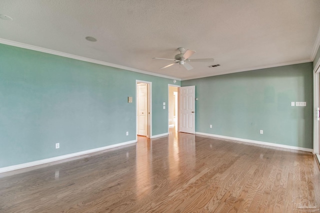 empty room with crown molding, a textured ceiling, a ceiling fan, baseboards, and visible vents