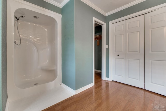 full bathroom featuring baseboards, walk in shower, ornamental molding, and wood finished floors