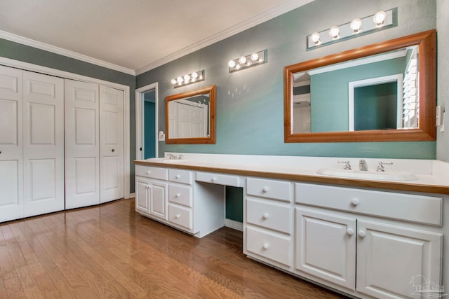 bathroom featuring double vanity, a sink, wood finished floors, and ornamental molding