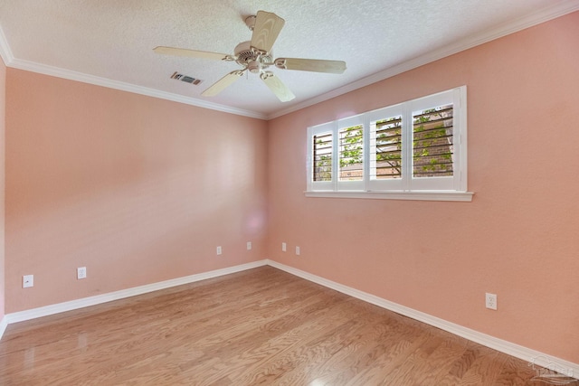 spare room with a textured ceiling, visible vents, ornamental molding, and wood finished floors