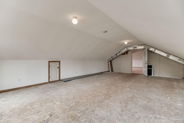 additional living space featuring carpet flooring, a textured ceiling, and vaulted ceiling