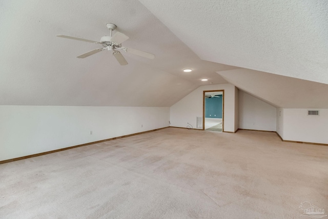 additional living space with a ceiling fan, visible vents, vaulted ceiling, baseboards, and light carpet