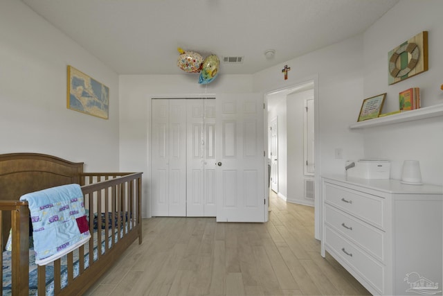 bedroom featuring light hardwood / wood-style floors, a closet, and a crib