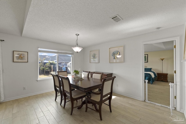 dining room featuring a textured ceiling and light hardwood / wood-style flooring