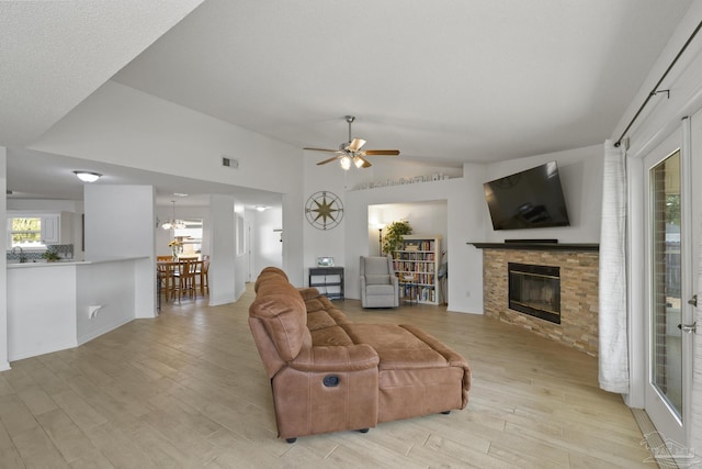 living room with lofted ceiling, ceiling fan with notable chandelier, and light hardwood / wood-style flooring