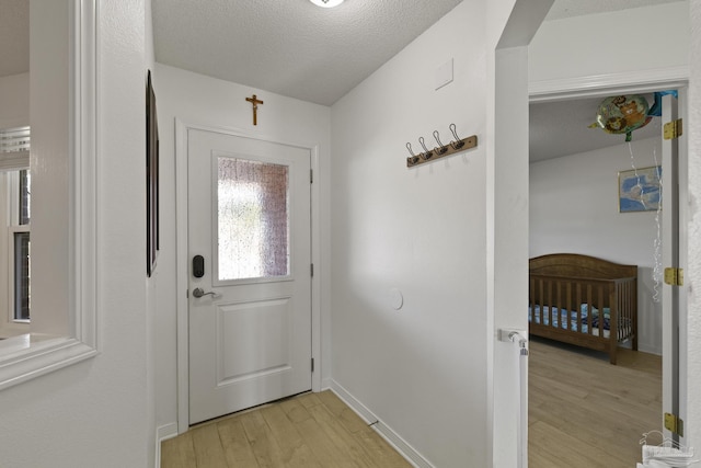 doorway with light hardwood / wood-style flooring and a textured ceiling