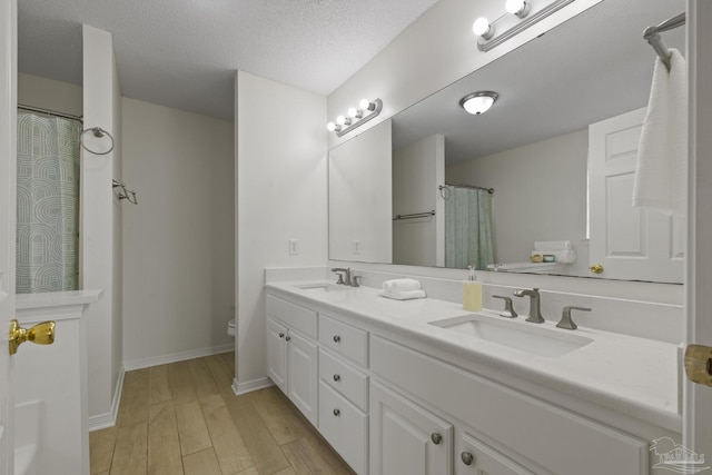 bathroom featuring wood-type flooring, toilet, vanity, and a textured ceiling