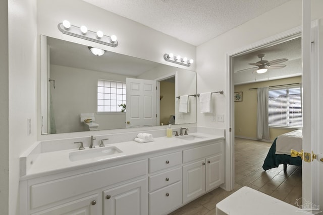 bathroom featuring ceiling fan, vanity, and a textured ceiling