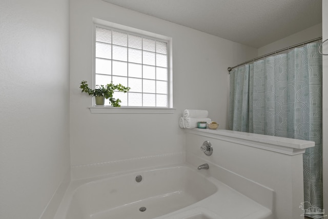 bathroom with a tub to relax in and a textured ceiling