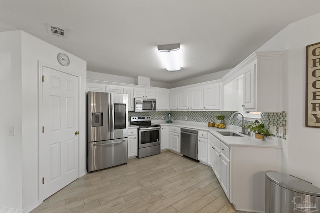 kitchen with tasteful backsplash, white cabinetry, appliances with stainless steel finishes, and sink