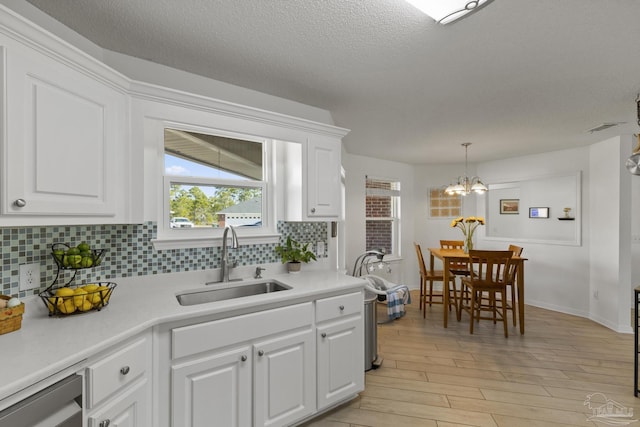 kitchen featuring sink, backsplash, hanging light fixtures, and white cabinets