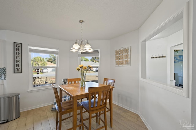 dining area featuring an inviting chandelier, a textured ceiling, and light wood-type flooring