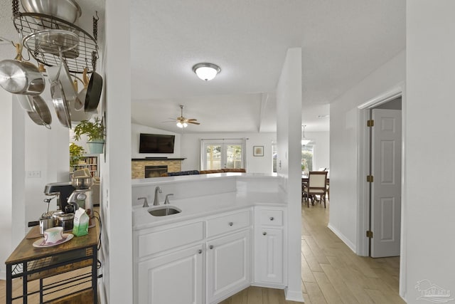 kitchen featuring ceiling fan, sink, white cabinets, and light wood-type flooring