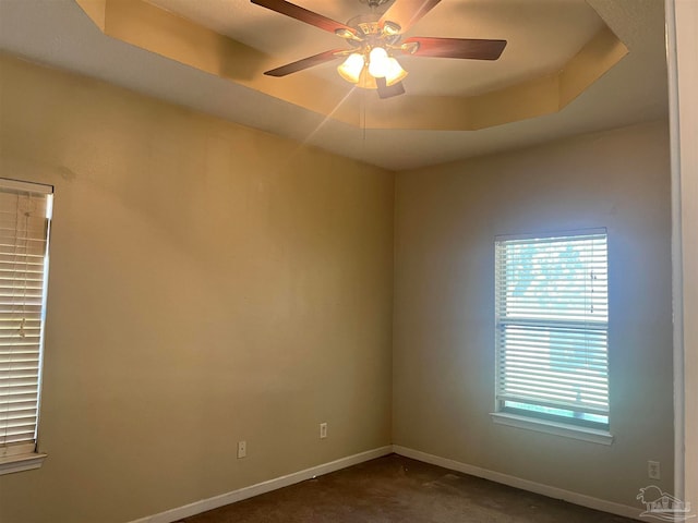 carpeted spare room with a tray ceiling and ceiling fan