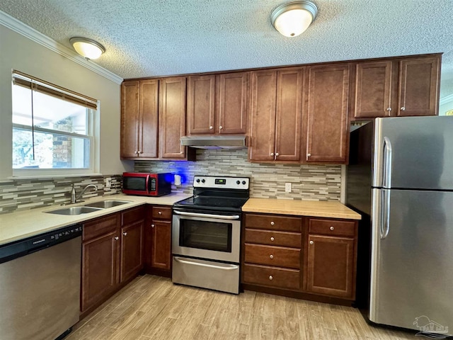 kitchen featuring stainless steel appliances, light countertops, light wood-style floors, a sink, and under cabinet range hood