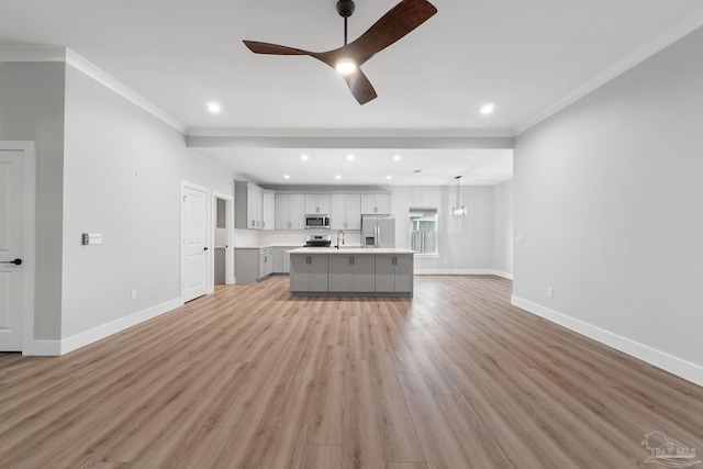 unfurnished living room with ceiling fan, sink, light wood-type flooring, and ornamental molding