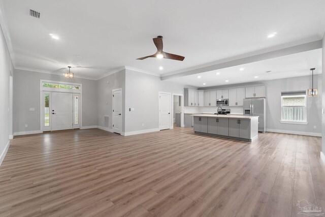 unfurnished living room with ceiling fan with notable chandelier, light hardwood / wood-style floors, sink, and crown molding