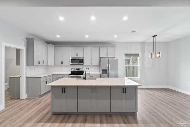 kitchen with gray cabinetry, light stone countertops, light hardwood / wood-style flooring, and appliances with stainless steel finishes